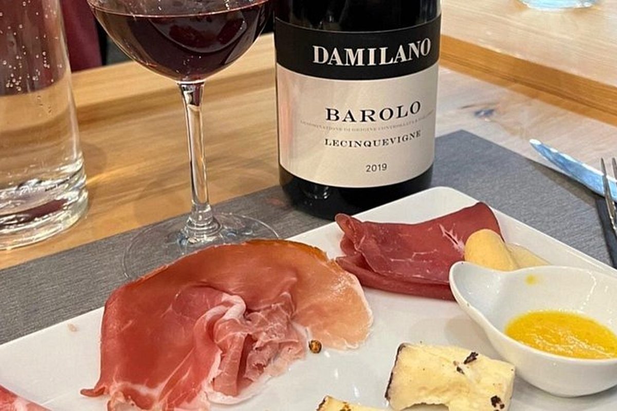 A bottle of Barolo beside prosciutto and cheese on a tasting plate