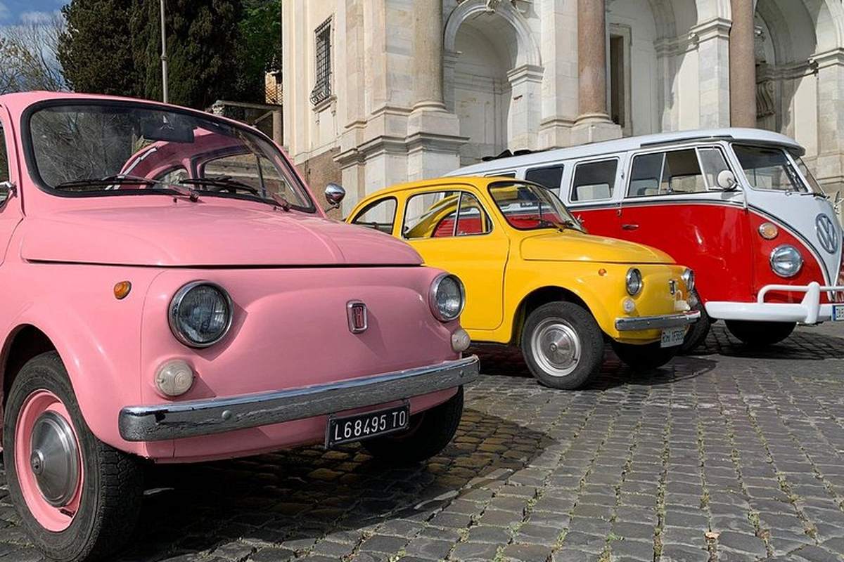 Three old Fiat 500s parked on a cobbled Roman street