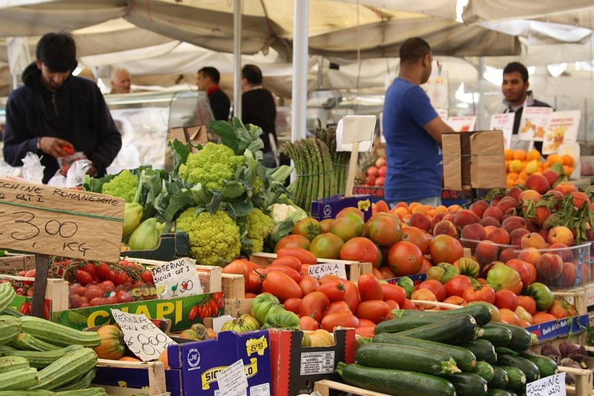 A Rome market stall stacked with courgettes, tomatoes and puntarelle
