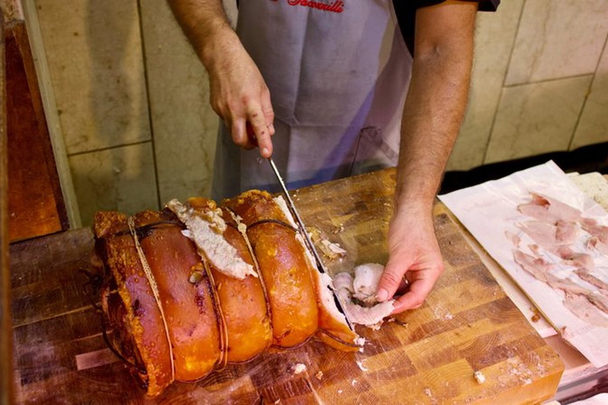 Porchetta being carved to order behind a Rome food counter