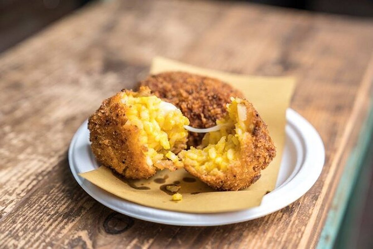 A suppli broken open, the mozzarella still stretching from the fried rice